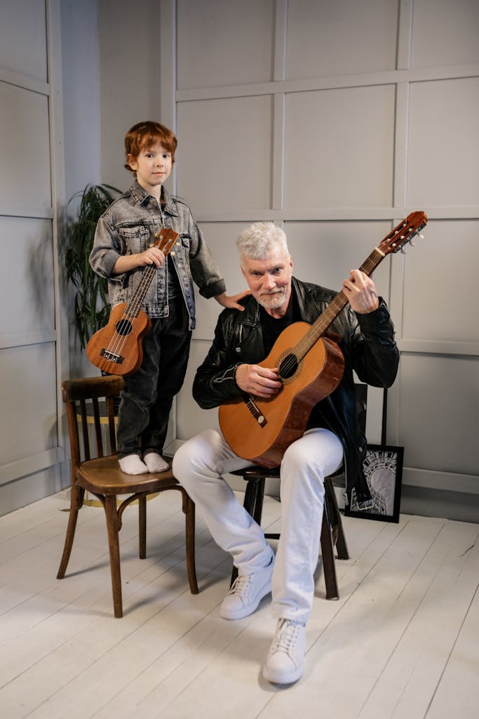 A grandfather and grandson enjoying music together with guitars indoors, showcasing family bonding and musical passion.